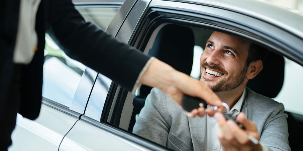 Hombre sonriendo recogiendo llaves de un coche